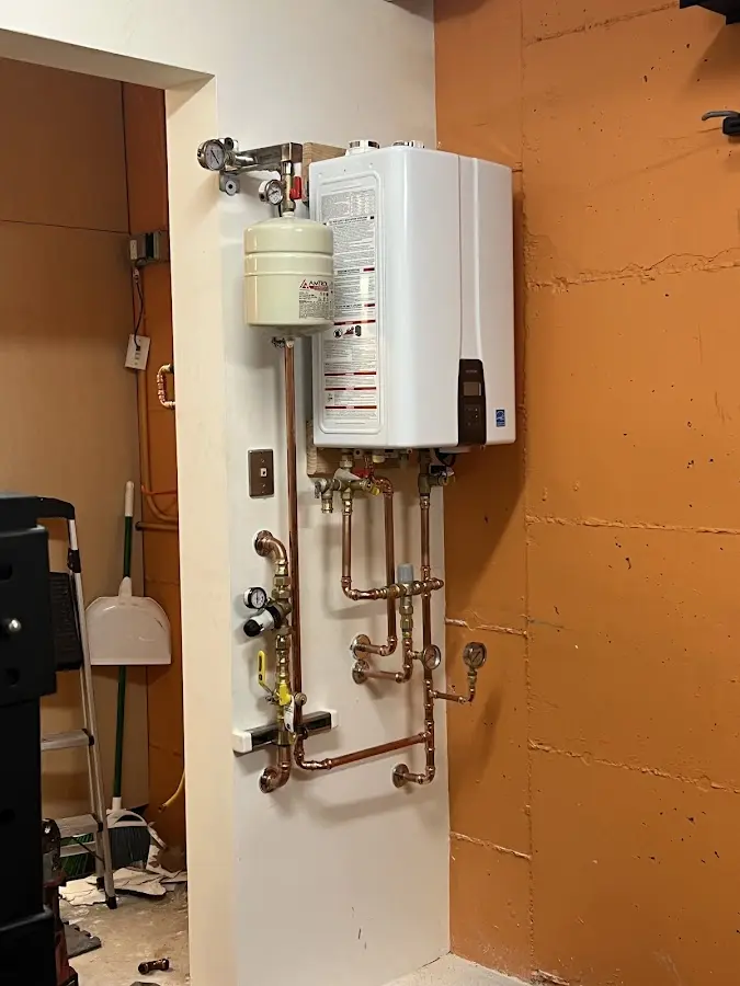 Plumbing technician inspecting water heater connections in Warren
